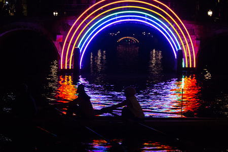Rowers pass by the artwork 'Bridge of the Rainbow "by Gilbert Moity in a canal on the boat route Watercolors at the Amsterdam Light Festival 2016の写真素材