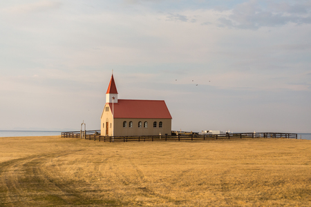 Church and graveyard in remote grassland on the Snaefellsnes peninsula coast against cloudy sky background, viewed in grazing light of the low evening sun. Located on Snaefellsnesvegur between Grundarfjordur and Olafsvik in West Icelandの写真素材