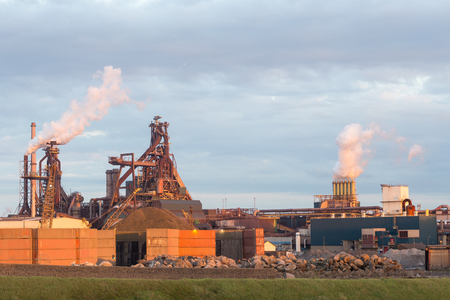 Old steel factory with smokestacks and chimney emissionsの写真素材