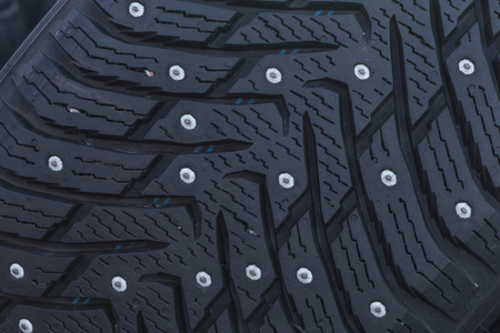 Close-up of a studded tire profile with spikes for winter driving on ice and snowの写真素材