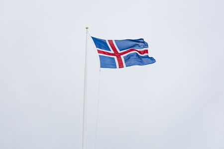 A civil flag and ensign Iceland against a clouded sky. The civil national flag of Icelanders is blue...