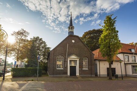 Small church and residential houses in a street in the small village Cuijk, the Netherlands. Autumn season, beautiful sunlight.の写真素材