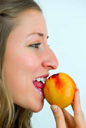 sweetly smiling girl eating a peachの写真素材