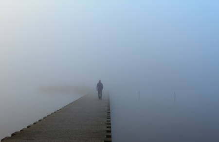 Man walking on a pier in the fog の写真素材