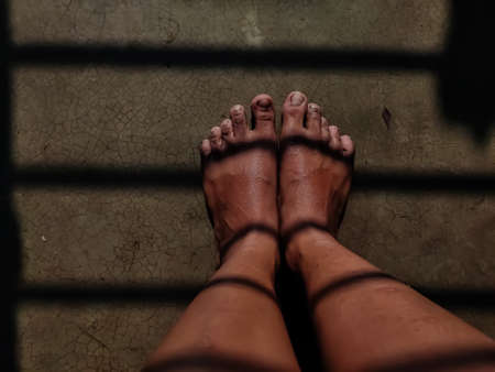 Sunlight and window shadows fall on the feet of a rural girl.の写真素材