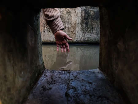 The reflection of a girl's hand fellon a water-filled cistern.の写真素材