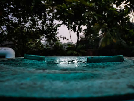 The morning light fell on the lid of a dew-filled water tank on the winter season.の写真素材