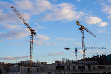 Construction cranes on a background of sky and cloudsの写真素材
