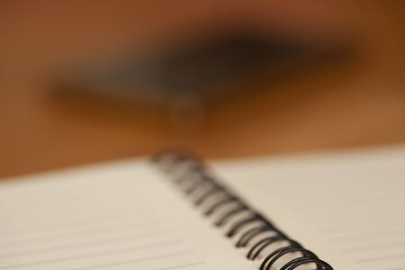 notebook with a spring telephone on the wooden tableの写真素材
