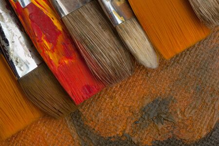 New and spoiled red and orange paint brushes