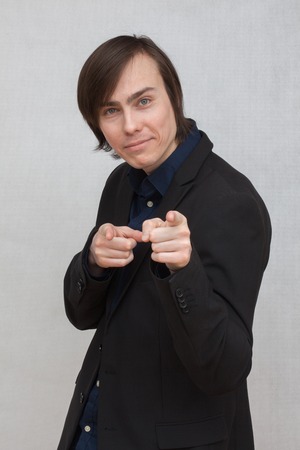 a young white man in a black jacket shows forefingersの写真素材