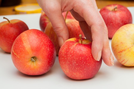 hand reaches for the apple, lying on a white backgroundの写真素材