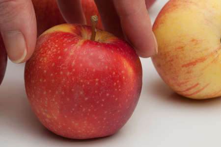 hand reaches for the apple, lying on a white backgroundの写真素材