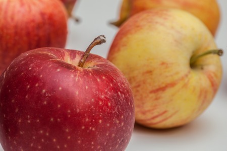 hand reaches for the apple, lying on a white background