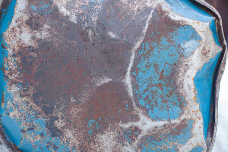 and crumpled rusty iron barrel with the bottom of the remnants of blue paint