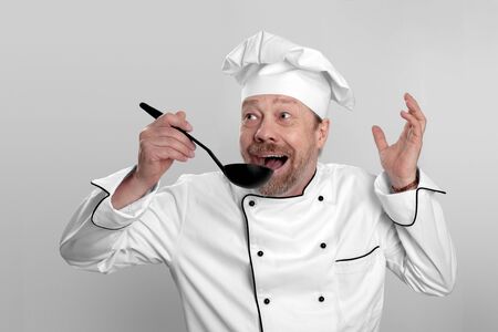 cook in white hat tasting the cooked them foodの写真素材