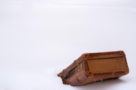 Old leather brown suitcase in the snowの写真素材