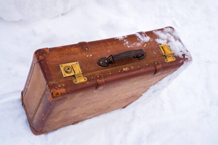 Old leather brown suitcase in the snowの写真素材