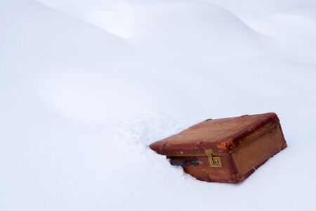 Old leather brown suitcase in the snowの写真素材