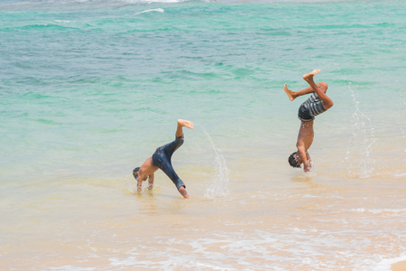 Two boys play in the water on the beach.のeditorial素材