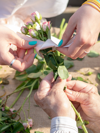 Female hands tie a ribbon on a bouquet of flowers.の写真素材