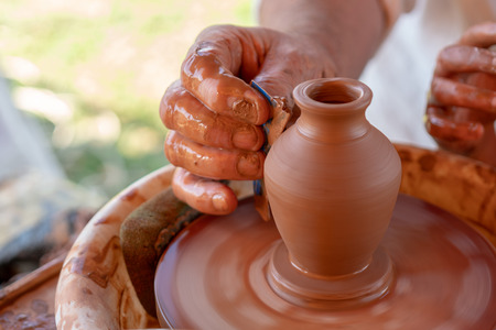 The master's hands make a pot on the potter's wheel.の写真素材