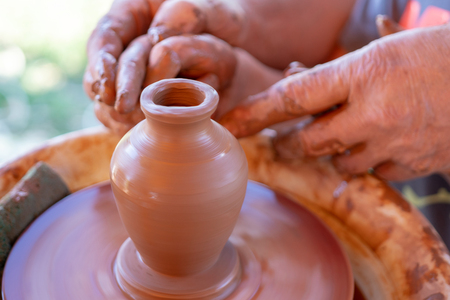 The master's hands make a pot on the potter's wheel.の写真素材