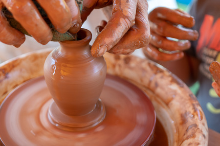 The master's hands make a pot on the potter's wheel.の写真素材