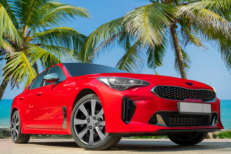Red car on a background of palm trees. Stylish, modern, bright image of the car for design solutions.の写真素材