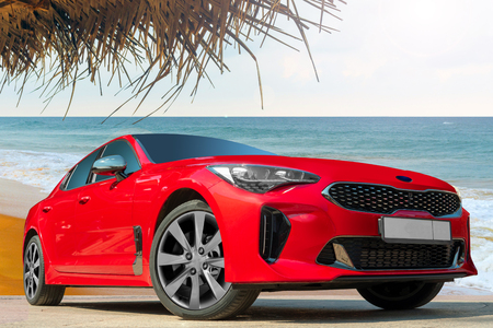 Red car on the background of the ocean. Stylish, modern, bright image of the car for design solutions.の写真素材