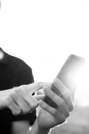 A smartphone is in the hands of a white young man.の写真素材