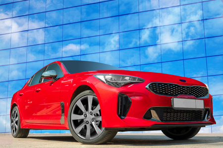 Red car on a blue sky background with white clouds. A stylish, modern, bright image of an avto mobile for design solutions.の写真素材