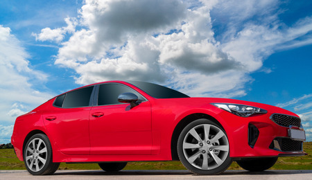 Red car on a blue sky background with white clouds. A stylish, modern, bright image of an avto mobile for design solutions.の写真素材