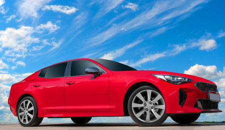 Red car on a blue sky background with white clouds. A stylish, modern, bright image of an avto mobile for design solutions.の写真素材