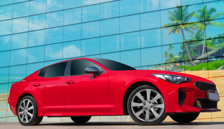 Red car on a background of palm trees. Stylish, modern, bright image of the car for design solutions.の写真素材