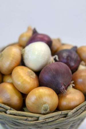 Yellow, red, white, ripe onions in a basket.の写真素材