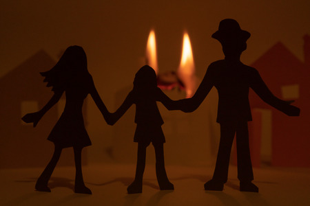 Cut from the paper family on the background of a burning paper house.の写真素材