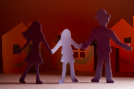 Cut from the paper family on the background of a burning paper house.