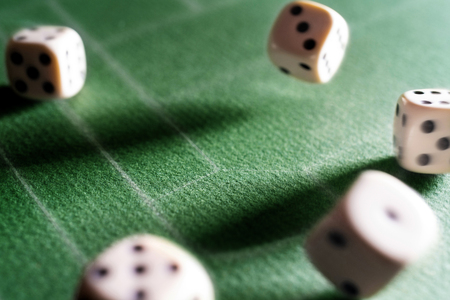 Dice game. Dice on the table. Illuminated with a contrasting light. Long shadows on the diagonal.の写真素材