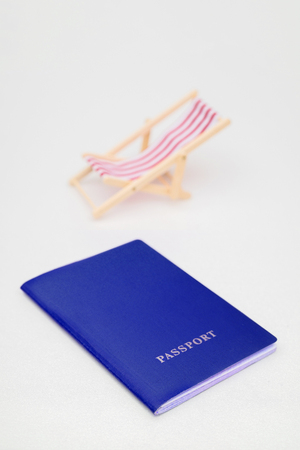 Blue passport and red beach chair on a white background.の写真素材