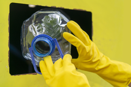 Hands in gloves throwing a plastic bottle. Garbage collection.の写真素材