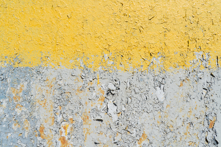 Yellow and gray cracked paint on a metal surface.の写真素材