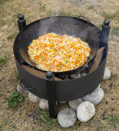 Cooking on an open fire. Stewed vegetables on fire.の写真素材