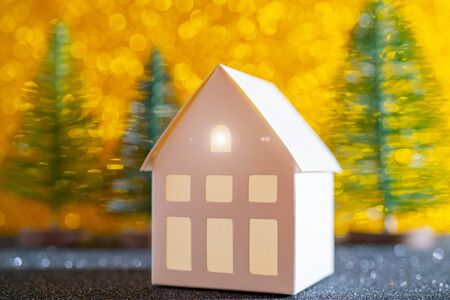 Green christmas tree on shiny background. Beautiful bokeh. Little white house.の写真素材