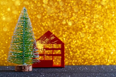 Green christmas tree on shiny background. Beautiful bokeh. Little red house.の写真素材