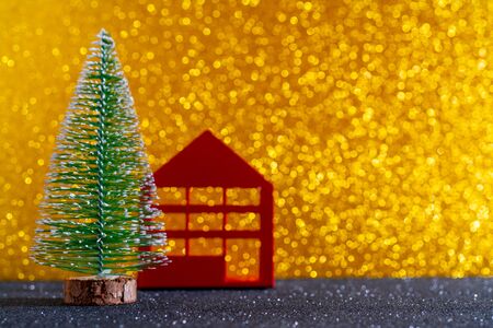 Green christmas tree on shiny background. Beautiful bokeh. Little red house.の写真素材
