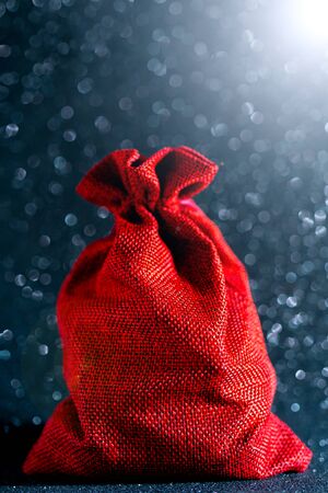 Christmas shiny black background. Red gift bag.  Beautiful bokeh.の写真素材