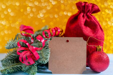 Christmas composition on a yellow background. Branches of spruce, bag with gifts, red serpentine and balls.の写真素材