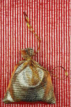 Shiny golden pouch on a red background. A gift on a holiday.の写真素材