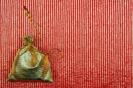 Shiny golden pouch on a red background. A gift on a holiday.の写真素材